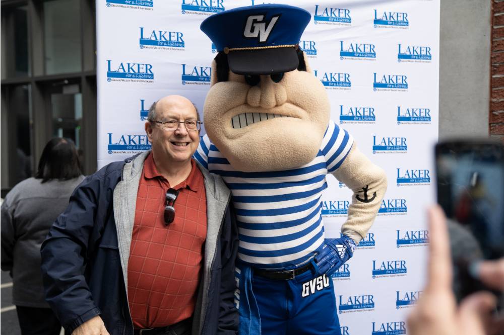 An alum poses with Louie the Laker